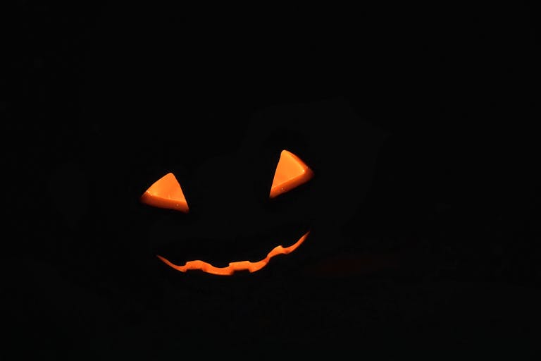 Spooky glowing Jack-O'-Lantern face in pitch black background, perfect for Halloween.