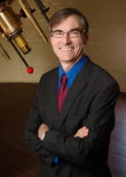 Professor Brian Fields in front of telescope.